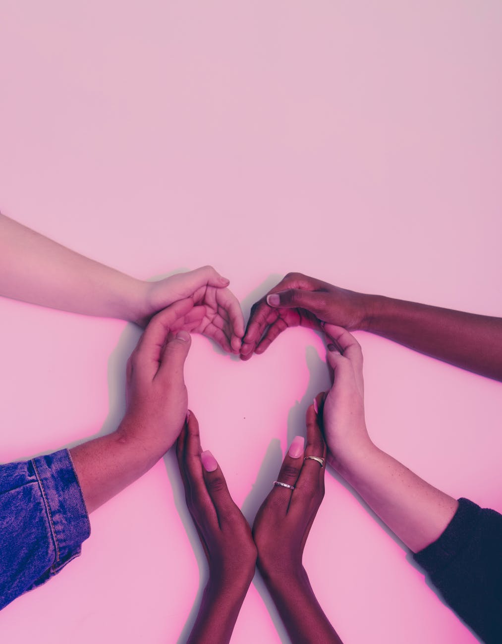 human hands forming heart on white surface
