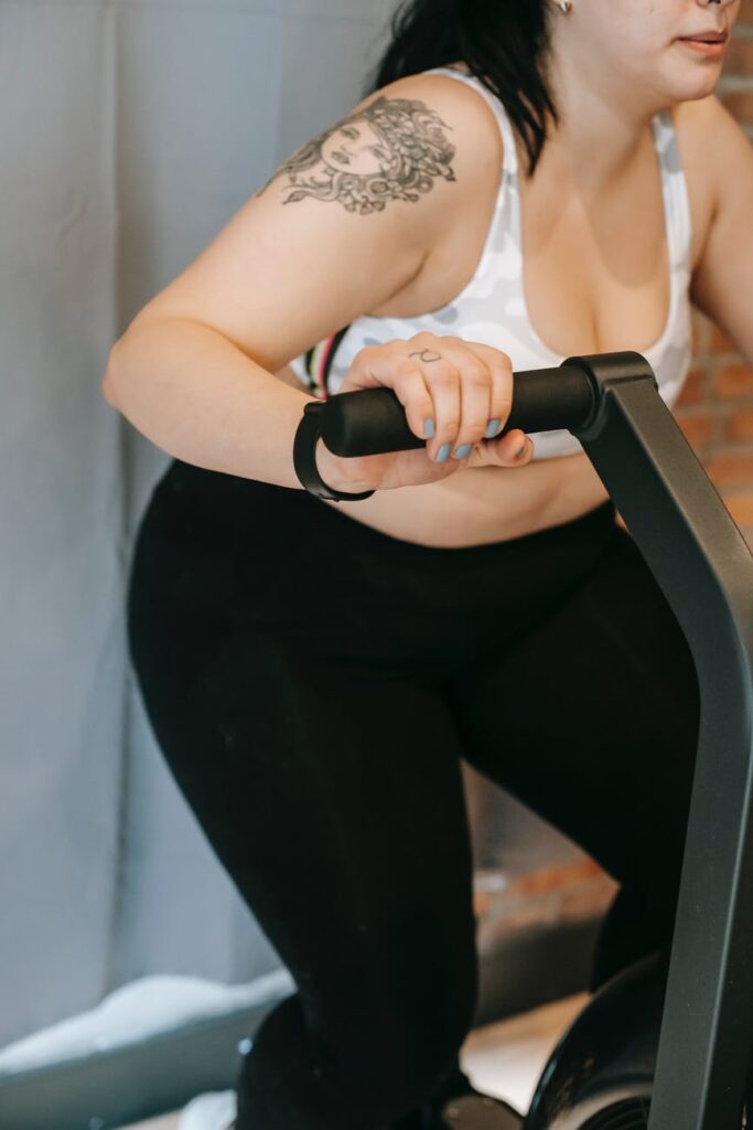 fat loss - anonymous overweight woman doing cardio exercise on cycling machine in gym