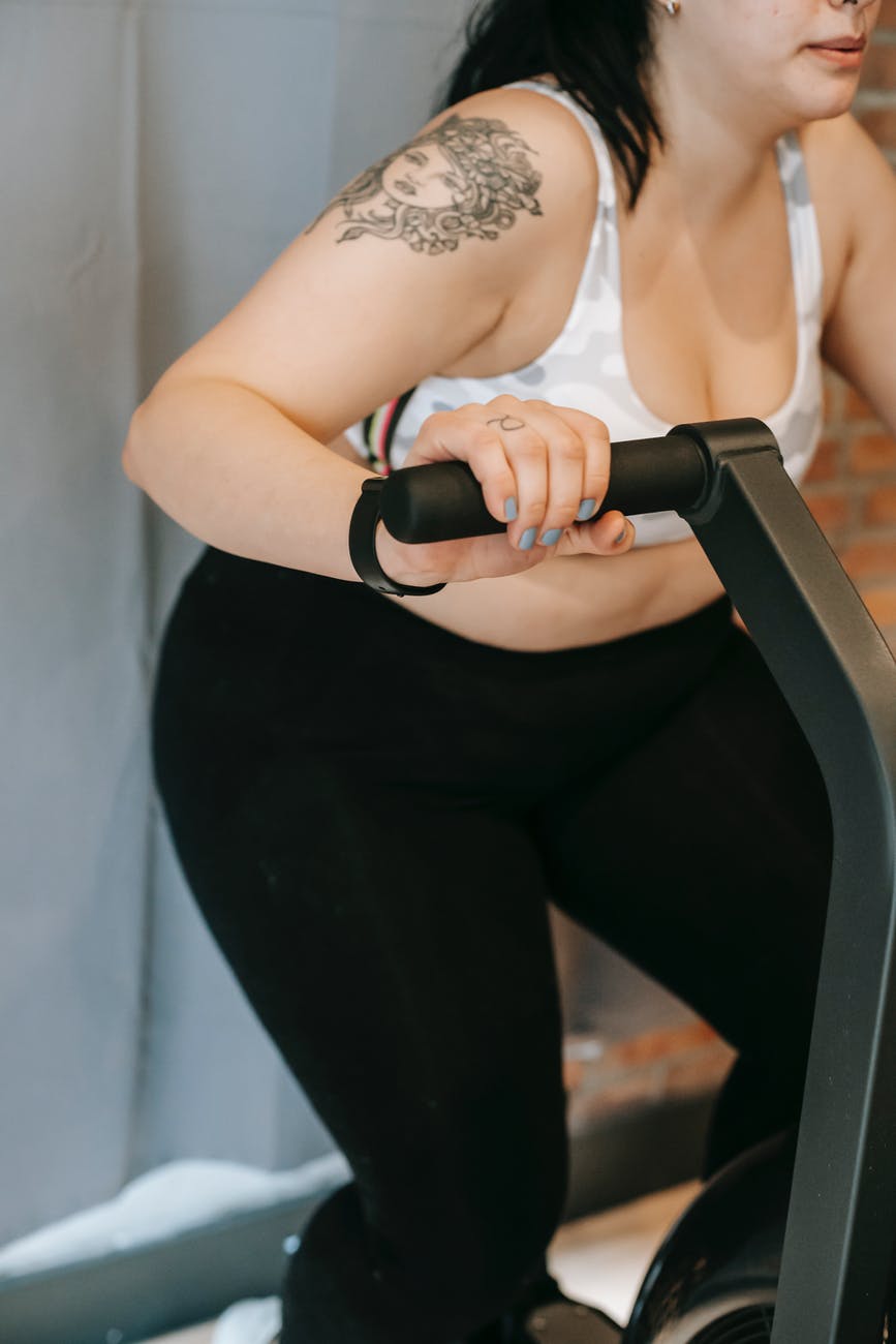 anonymous overweight woman doing cardio exercise on cycling machine in gym